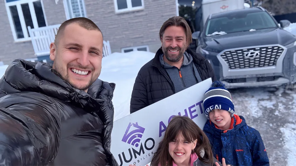 Famille cliente de Jumo Immobilier avec la pancarte « Acheté » en hiver